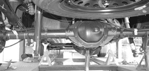 Rear axle and frame supported on jack stands with a floor jack under the axle center
